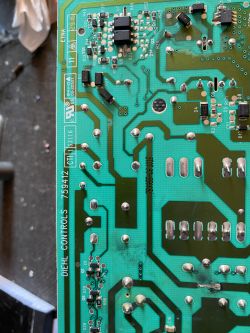 Zbliżenie na płytkę drukowaną z oznaczeniami i komponentami elektronicznymi.
