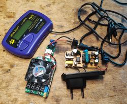 Tester ESR, zasilacz i sztuczne obciążenie na drewnianym stole.