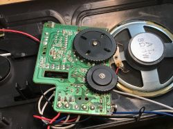 Radio Interior with PCB and Speaker A circuit board with two black gears and a visible 8Ω speaker inside an opened radio case.