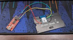 Circuit Board with CB3S Module and Adapter Circuit board with a CB3S module connected by wires to an adapter on a computer mat background.