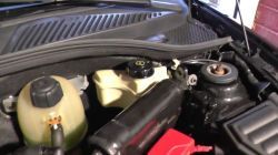 View of a car engine compartment with visible fluid reservoirs.