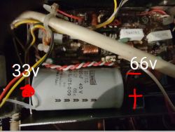Wnętrze urządzenia elektronicznego z widocznym kondensatorem oznaczonym napięciami 33V i 66V.