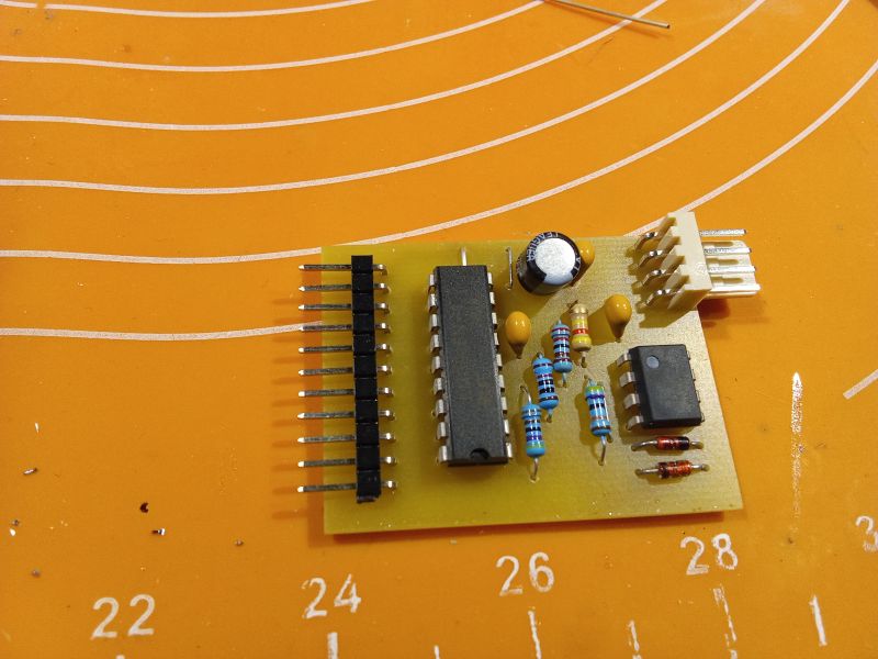 Printed circuit board with electronic components on an orange background with curved white lines and numbers.