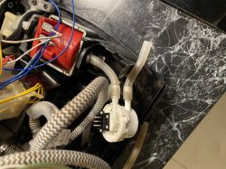 View of the interior of a coffee machine with visible tubes and wires.