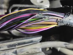Close-up of damaged wire harness with frayed insulation on multiple colored cables