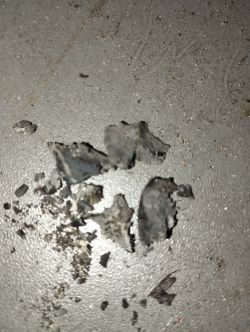 Fragmenty spalonych resztek na metalowej powierzchni.