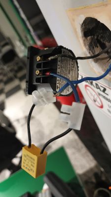 Smart switch module in a wall box with connected wires and a yellow capacitor on connectors