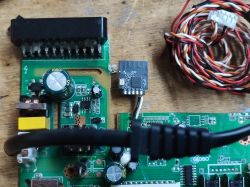 Close-up of an electronic board with various components and a coil of wires.