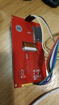 Back of a red display PCB with an FFC ribbon connector and multicolor wires on a wooden surface