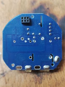 Blue PCB with visible traces and solder points, lying on a wooden surface.