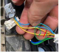 A hand holding a bundle of wires with yellow, blue, green, and red wires.