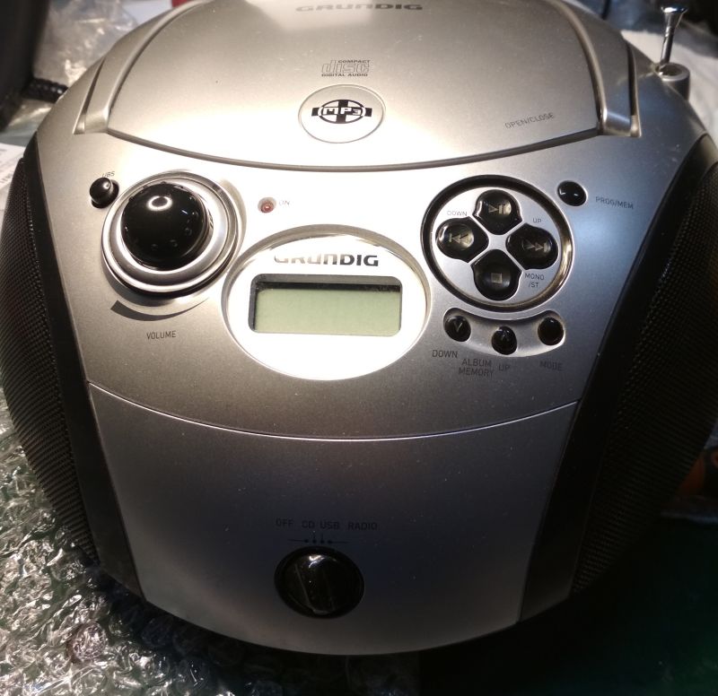 Widok panelu przedniego srebrnego radioodtwarzacza Grundig RCD 1445 USB z widocznymi przyciskami i pokrętłami.