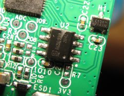 Close-up of a green circuit board with a soldered integrated circuit.