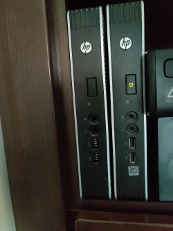 Two HP T610 terminals placed side by side on a wooden shelf, with front panels featuring ports.
