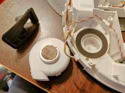 Dismantled parts of a robotic vacuum with a dust-covered blower.