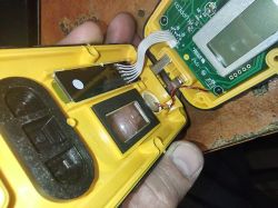 Wnętrze żółtego urządzenia: płytka PCB z wyświetlaczem i moduł optyczny z soczewką