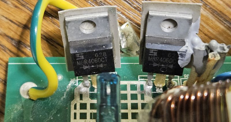 Dwa uszkodzone tranzystory MBR4060 na płytce PCB, nadtopione i z widocznymi śladami przegrzania.