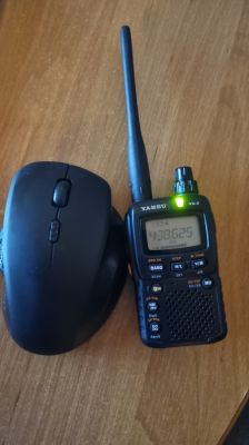 Ręczne radio Yaesu VX-2R obok czarnej myszy komputerowej na drewnianym blacie