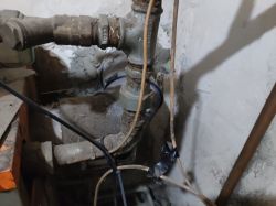 Zbliżenie na stare zawory i rury instalacji hydraulicznej w piwnicy