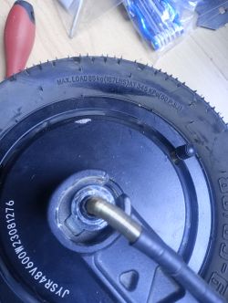 Zbliżenie koła hulajnogi Motus Pro 10 2022 z problemem przy odkręceniu śruby z przewodem zasilającym.