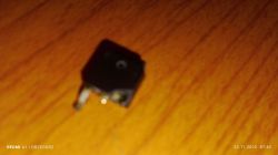 Niewyraźne zbliżenie uszkodzonego elementu elektronicznego na drewnianym blacie.