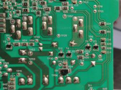 Close-up of a green printed circuit board with visible markings of electronic components.