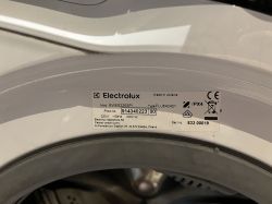 Tabliczka znamionowa pralki Electrolux z widocznym modelem oraz numerem seryjnym na białej obudowie urządzenia.