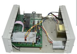 Widok wnętrza metalowej obudowy urządzenia elektronicznego z wieloma przewodami i płytką PCB.