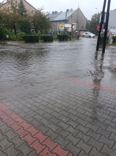 Ulica zalana wodą z powodu powodzi z widocznym znakiem stopu.