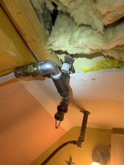 Instalacja hydrauliczna z widocznym trójnikiem i zaworem przy zbiorniku wyrównawczym.