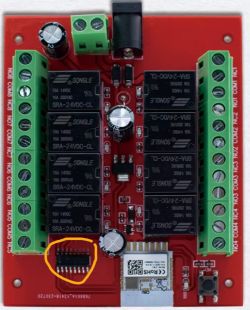 Red electronic board with green connectors, relays, and markings.