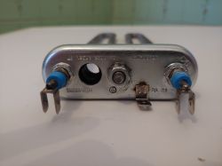 Grzałka do pralki Electrolux leżąca na białej powierzchni.