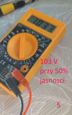 Zbliżenie na miernik pokazujący 103,3 V przy 50% jasności LED
