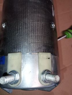 Zbliżenie na szczotkowy silnik elektryczny do quada z widocznymi złączami śrubowymi.