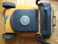 Elektryczna kosiarka ogrodowa w żółto-czarnej obudowie z widocznym przezroczystym okienkiem inspekcyjnym na górze.