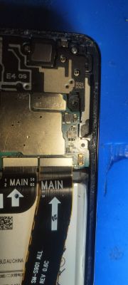 Zdjęcie wnętrza telefonu Samsung S22 5G, pokazujące elementy elektroniczne obok tasiemki sygnałowej.
