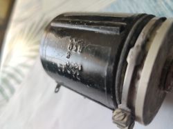 Zbliżenie czarnego cylindrycznego elementu z wytłoczonym napisem i metalową obejmą