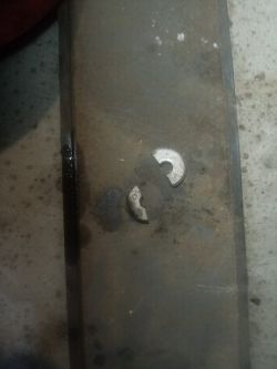 Dwa metalowe fragmenty na podłożu z widocznymi zabrudzeniami.