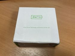 A white box on a wooden table with the words SWITCH and Show Future Technology and Embrace Smart Life.