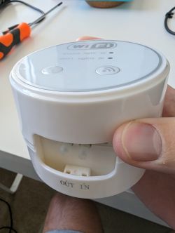 Wi-Fi Enabled Water Pump The image shows a hand holding a small white water pump with two buttons and Wi-Fi symbols on its front panel.
