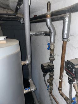 Instalacja grzewcza w piwnicy z rurami i pompą GRUNDFOS