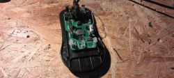 Otwarta mysz komputerowa z widoczną płytką PCB na drewnianym blacie
