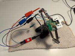 Testing an Electrical Socket PCB A PCB of an electrical socket with test wires connected, held in a helping hand tool.