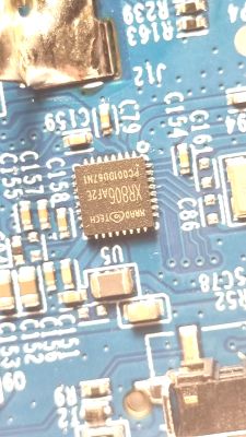 Macro photo of a blue PCB with an integrated circuit and surrounding SMD components.