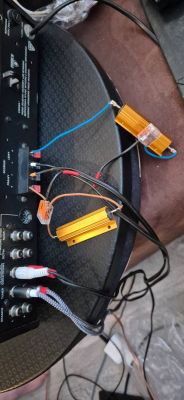 Zbliżenie na wzmacniacz audio z podłączonymi złotymi rezystorami i przewodami.