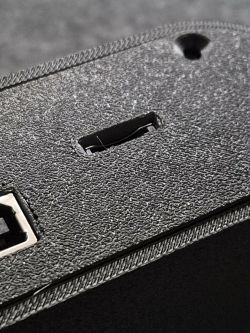 Close-up of a black textured device casing with a small slide switch and a round hole