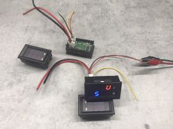 Three electronic meters with colorful wires on a concrete surface.