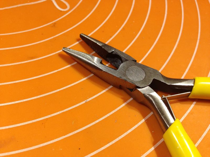 Kombinerki z żółtymi uchwytami na pomarańczowym tle.