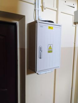 Plastikowa rozdzielnica elektryczna ZPL-1 zamontowana na ścianie, z rurami prowadzącymi do niej od góry i dołu.