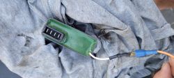Zielony moduł złącza elektrycznego z czterema pinami, trzymany nad szmatką.
